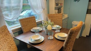Une table à manger dressée avec des assiettes, des verres et un vase de fleurs.