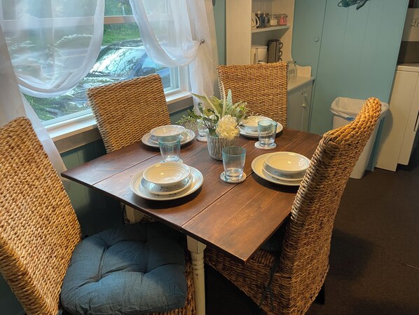 A dining table set with plates, glasses, and a vase of flowers. - The Bluffs Cottage (Roque Bluffs)