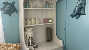 Une salle de bain avec un meuble blanc, un panier en osier et des éléments décoratifs muraux.