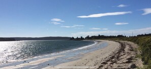 A beach with a sandy shore and calm water. - The Bluffs Cottage (Roque Bluffs)