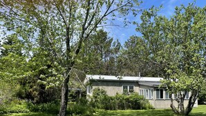 Une maison à deux étages, dotée d’un toit en pente, entourée d’une pelouse bien entretenue et d’arbres.