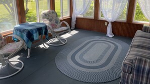 Une pièce chaleureuse avec un tapis rond, une table recouverte d’une nappe bleue, un fauteuil à motifs floraux et un canapé.