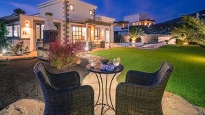 A modern house with a patio, two wicker chairs, and a small table with drinks. - *Luxury Villa* | Heated Pool, Sea & Mountain Views - High Speed WIFI. (Playa Blanca)