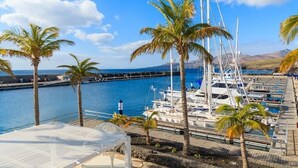 A marina with boats docked, palm trees, and a clear blue sky. - *Luxury Villa* | Heated Pool, Sea & Mountain Views - High Speed WIFI. (Playa Blanca)