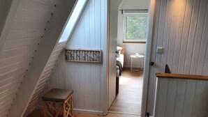 Habitación con techo bajo inclinado, banco de madera, una mesa pequeña y un adorno en la pared.