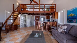 A spacious living area with a high ceiling, a wooden staircase, a kitchen, and a dining area. - Beach and Oceanfront apartment Casa Mar Y Sol (San Pedro)