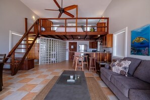 Un vaste espace de vie doté d’un haut plafond, d’un escalier en bois, d’une cuisine et d’un coin repas.
