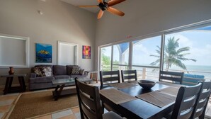 A dining area with a view of the ocean, a ceiling fan, and artwork on the walls. - Beach and Oceanfront apartment Casa Mar Y Sol (San Pedro)