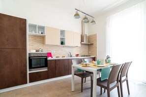 Een koelkast, een oven, een kookplaat, een eettafel