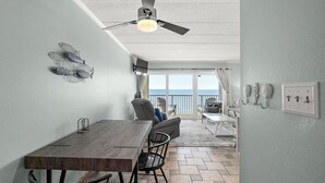 Un comedor con mesa y sillas, un ventilador de techo y vistas al exterior.