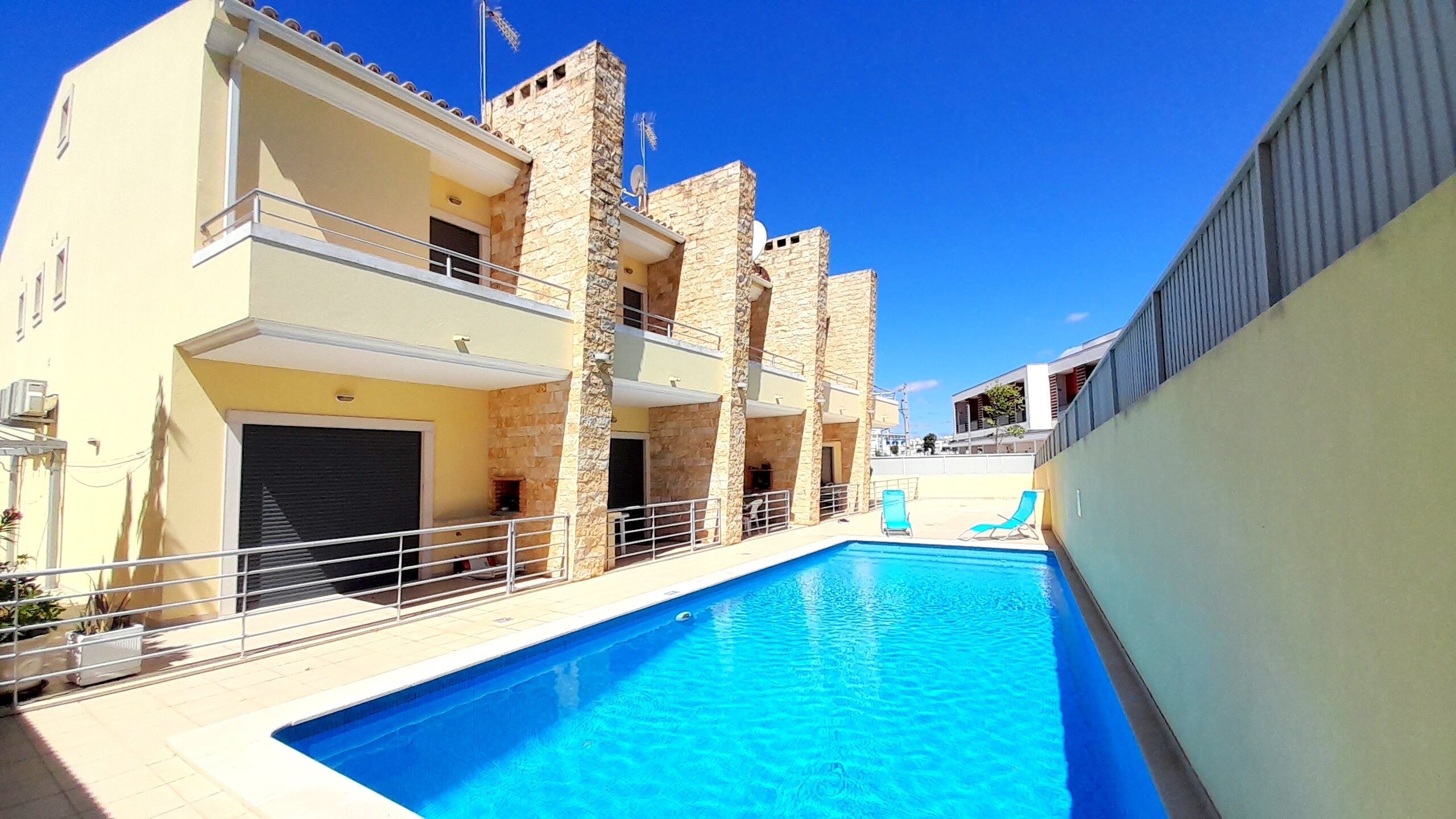 A swimming pool adjacent to a building with balconies and a stone facade.