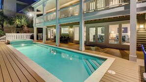 A two-story building with a swimming pool, outdoor seating, and a covered patio area.