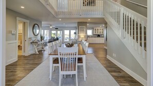 A spacious interior with a dining area, kitchen, and a staircase leading to an upper level.