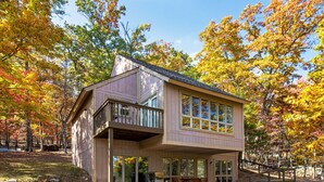 Une maison à deux étages dotée d’un balcon, de grandes fenêtres et d’un patio couvert.