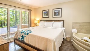 Une chambre d’hôtel avec un grand lit, une salle de bain avec baignoire et une vue sur l’extérieur par les fenêtres.
