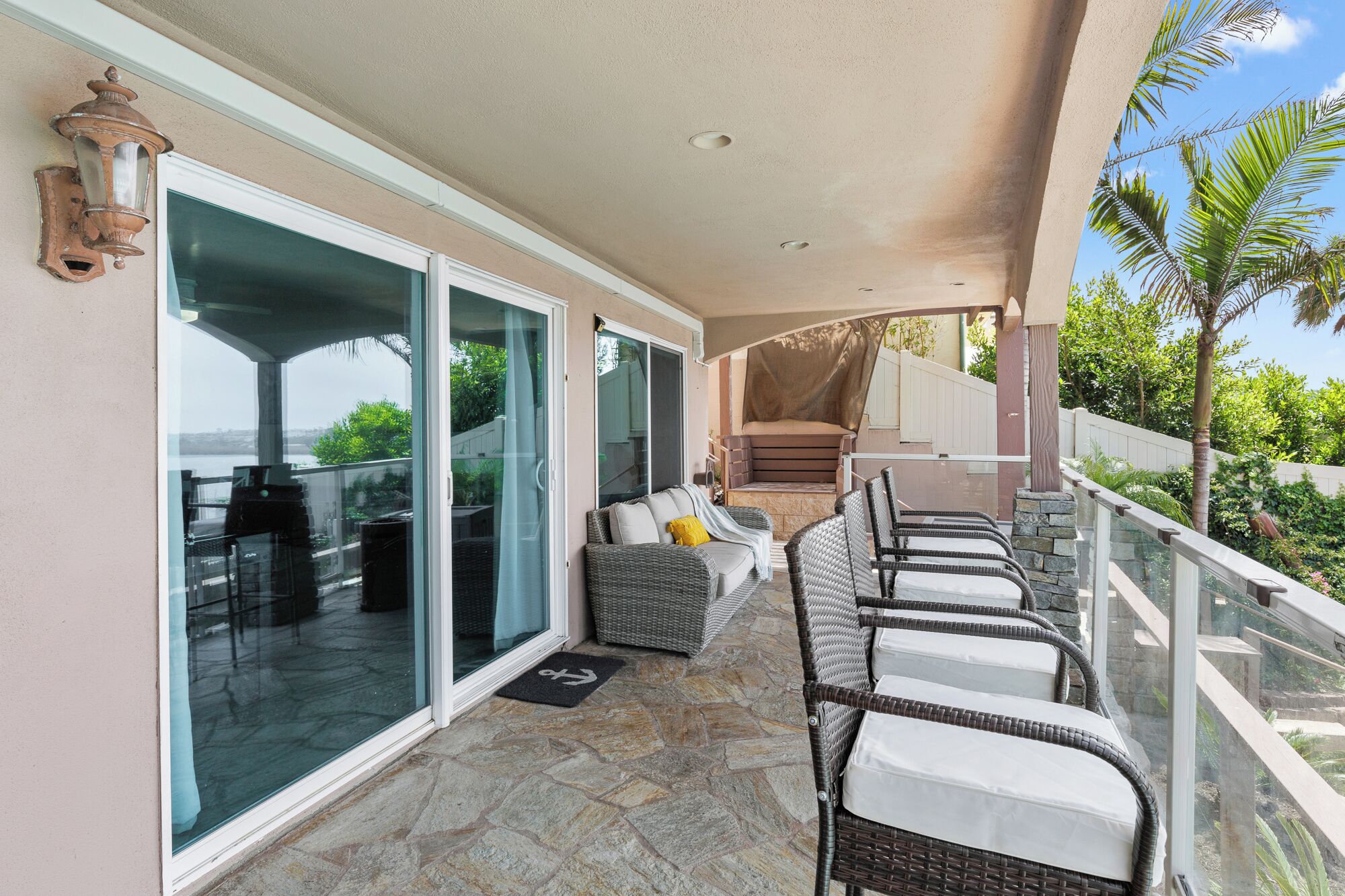 A covered balcony with wicker furniture, a sliding glass door, and a view of the ocean.