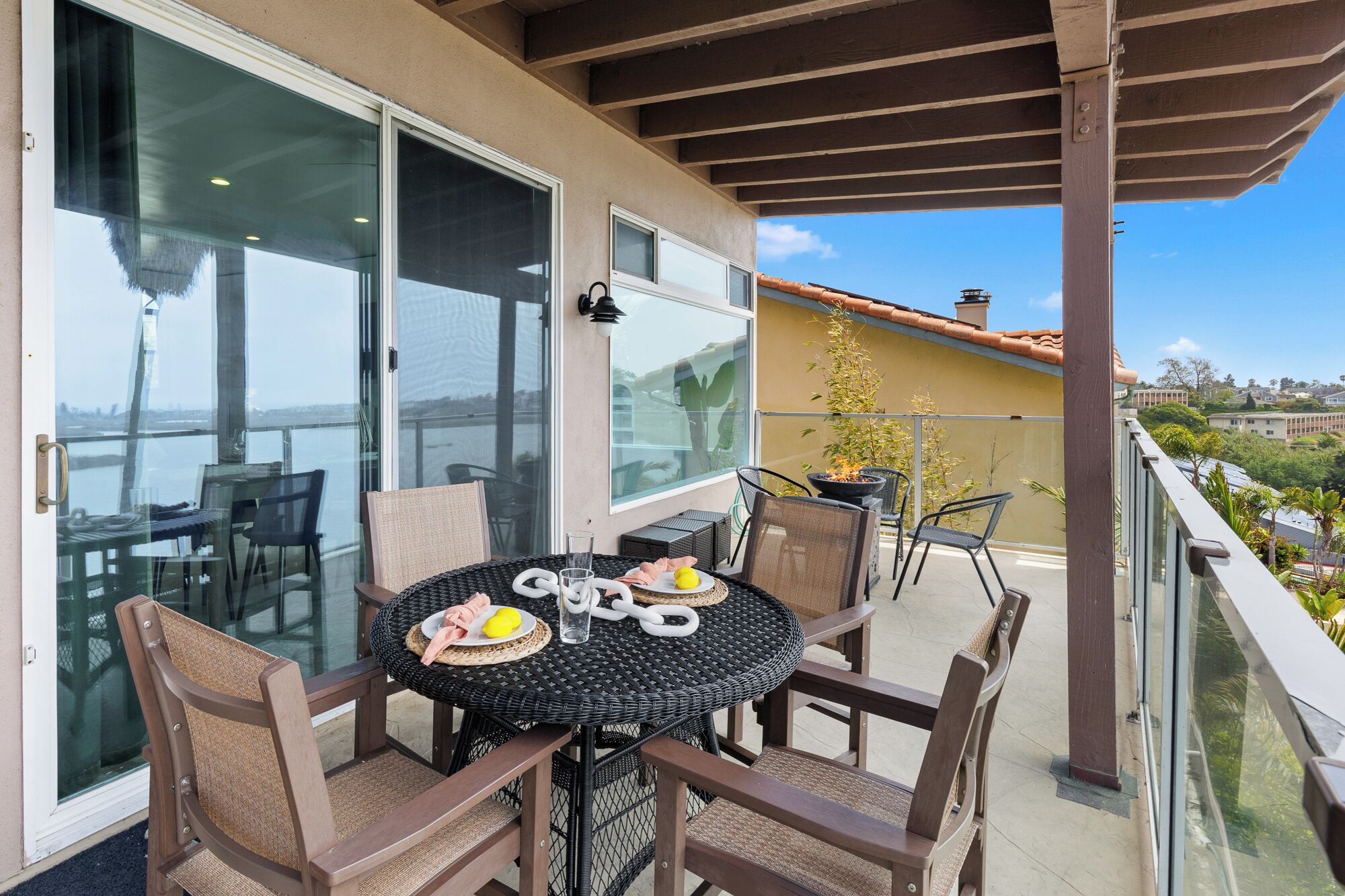 A balcony with a round table and chairs, a glass door, and a view of the city.
