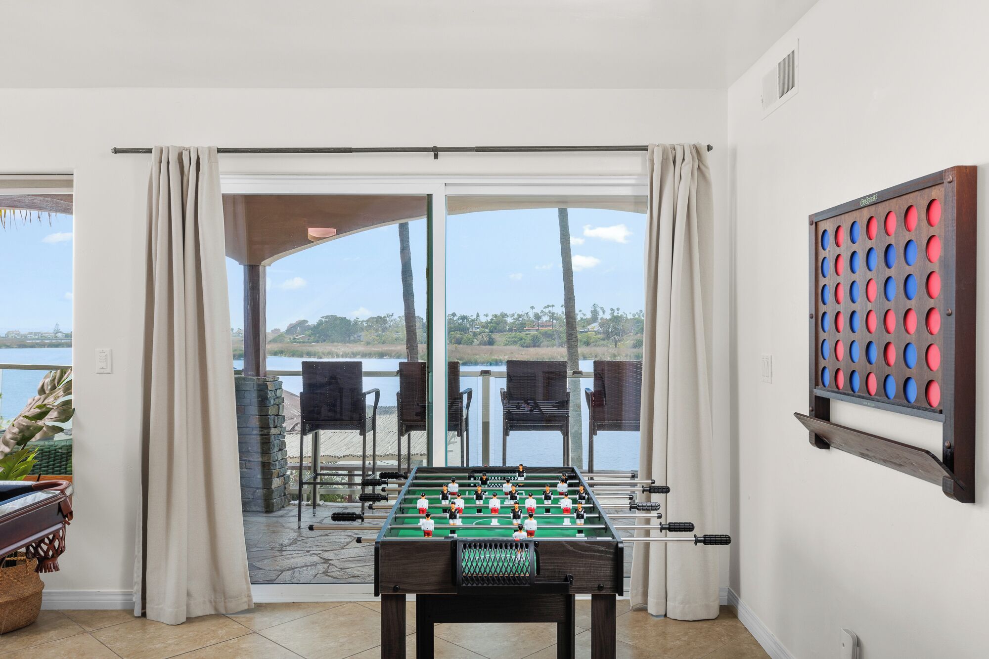 Una mesa de fútbolín en una habitación con vista a un lago y palmeras.