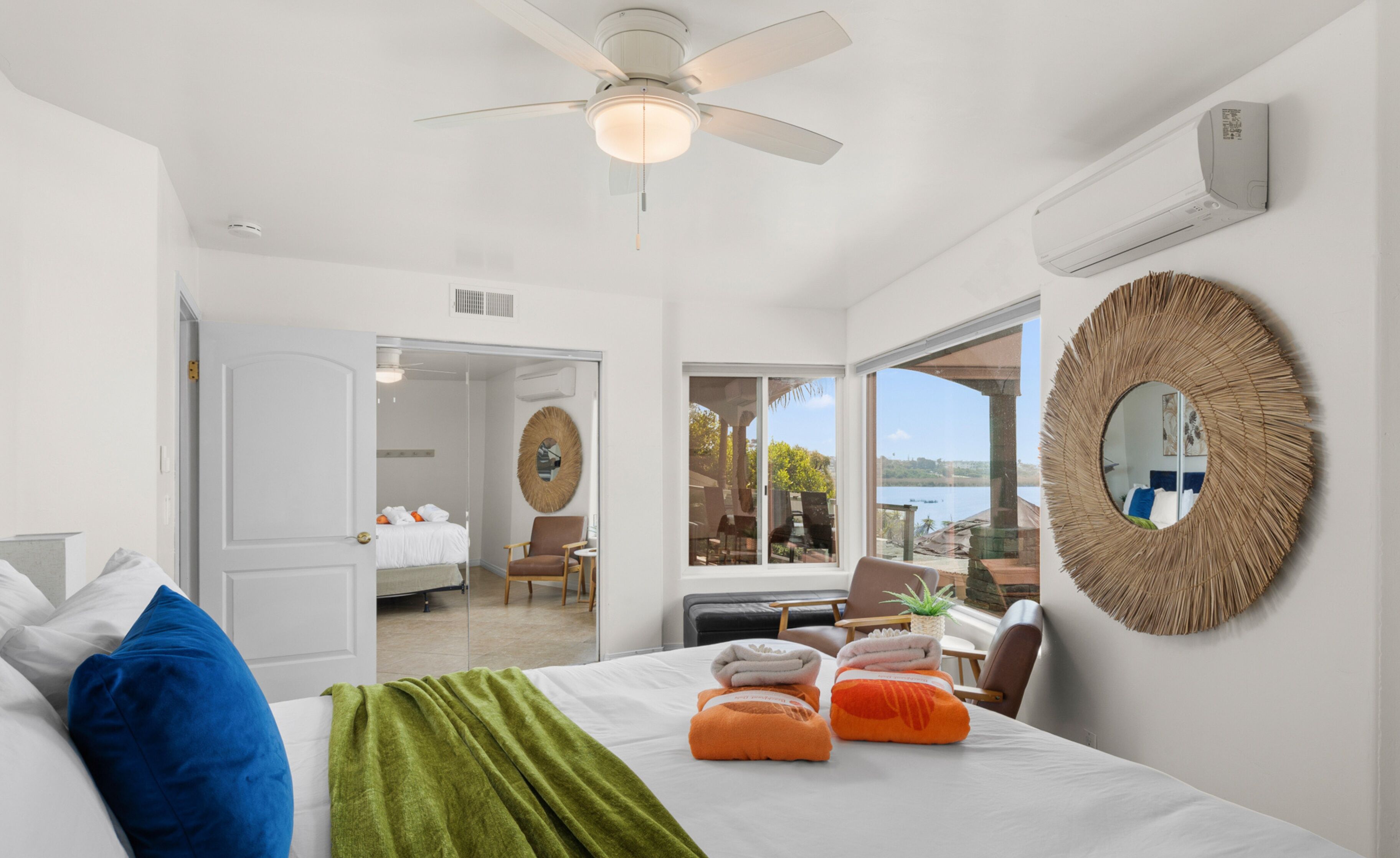 A hotel room with a bed, a ceiling fan, a large mirror, and a view of the outdoors.