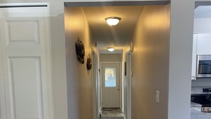 A narrow hallway with wooden flooring, white walls, and a ceiling light. - Adorable 2 Bedroom Vacation Rental Located on Canal (Algonac)