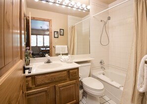 A bathroom with a double sink, a toilet, a bathtub, and a shower.