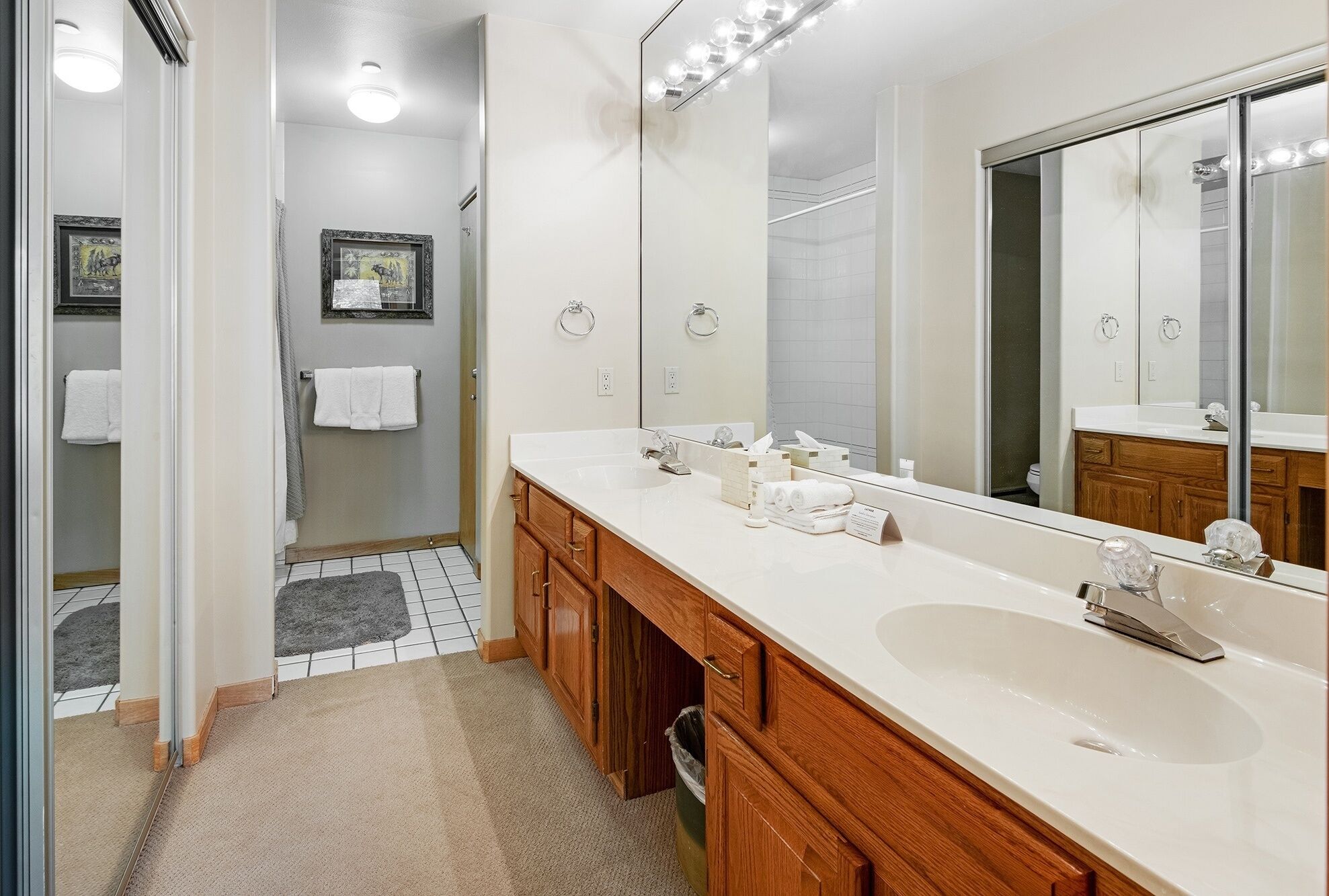 A modern bathroom with two sinks, a large mirror, and a shower area.