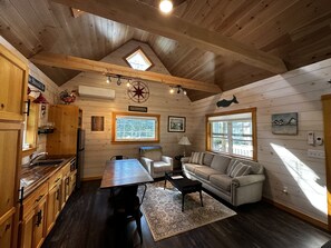 Een gezellig chalet interieur met houten details, een eethoek, een bank en een raam met uitzicht.