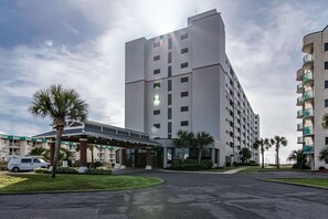 A modern hotel with a central entrance, multiple floors, and a parking area.