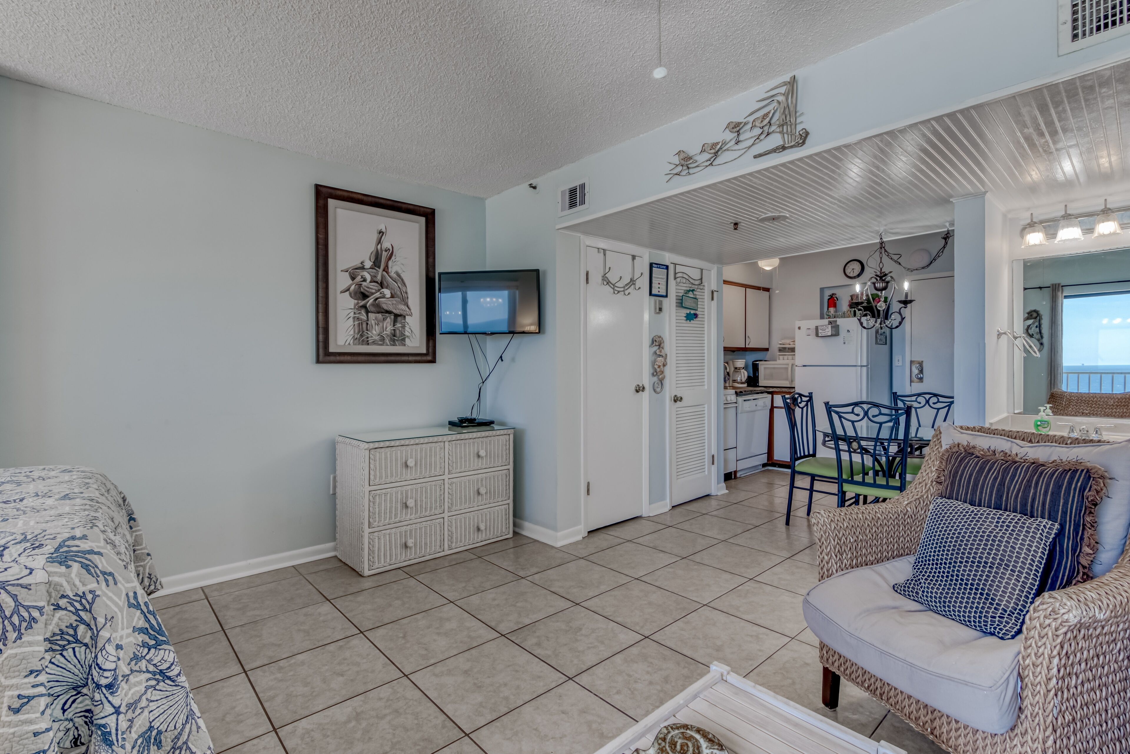 A spacious living area with a large bed, a television, a white cabinet, and a dining area with chairs and a table.