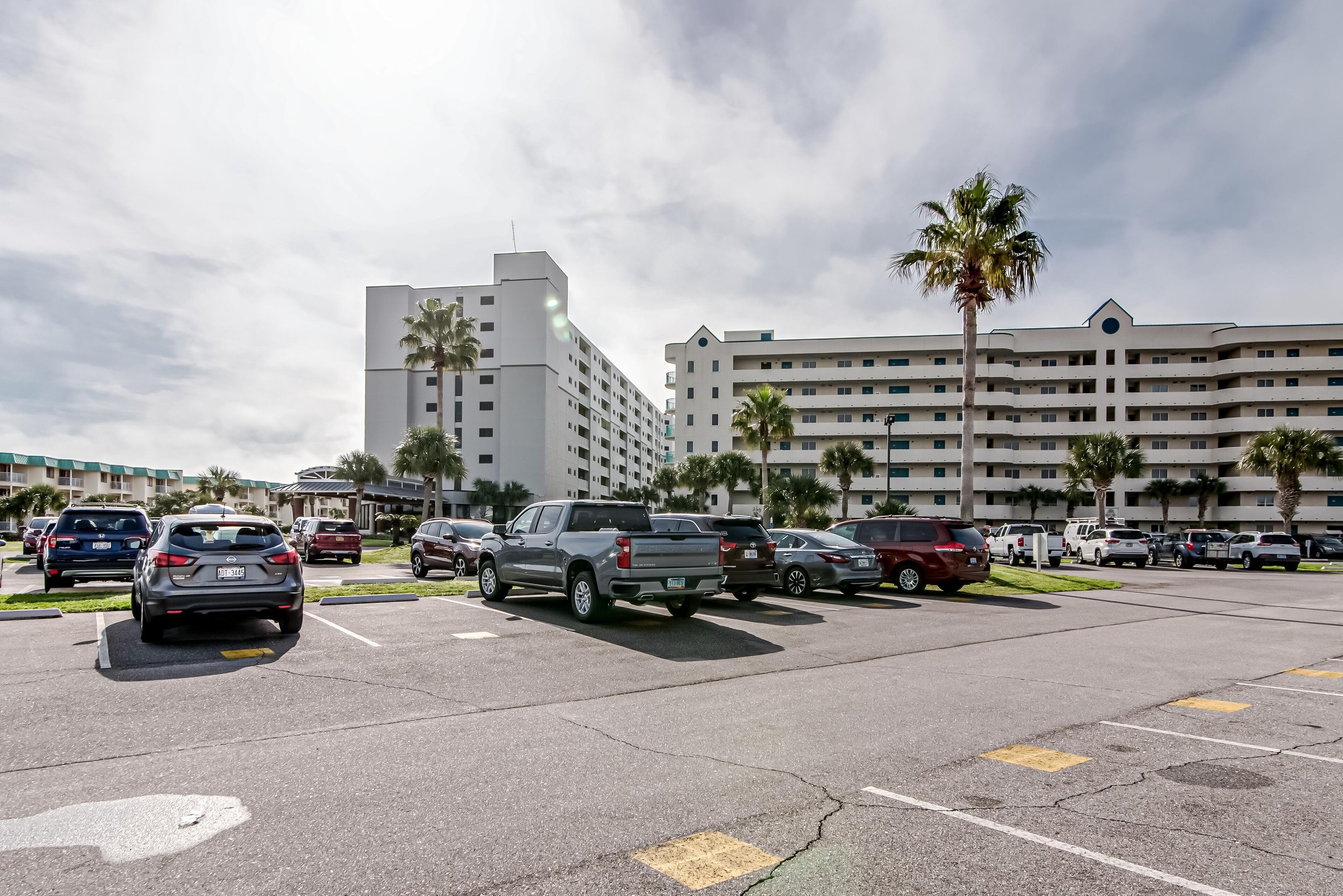 A parking lot with multiple cars and a large hotel building in the background.