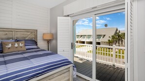 A bedroom with a bed, pillows, and a nightstand. - Gulf View, Ground Floor TH on West End of Mexico Beach ~ Set Sail at 5 (Mexico Beach)