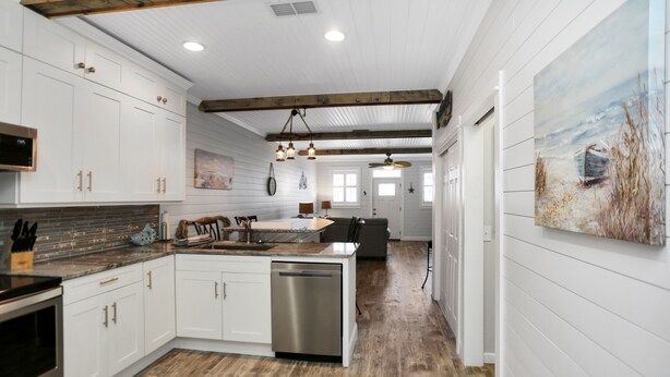 A modern kitchen with white cabinetry, a central island, and a wooden ceiling. - Gulf View, Ground Floor TH on West End of Mexico Beach ~ Set Sail at 5 (Mexico Beach)