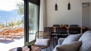 Una sala de estar moderna con comedor, ventanas amplias y vistas a montañas.