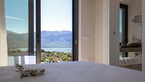 Un dormitorio con un ventanal que ofrece vistas a un lago y montañas.