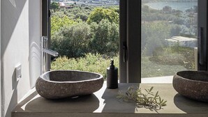 Un baño con dos lavamanos de piedra y vistas a un paisaje montañoso.