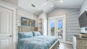 A bedroom with a bed, a ceiling fan, a window, and a TV.