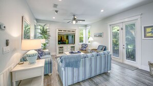 A spacious living room with a large sofa, a television, and a ceiling fan.