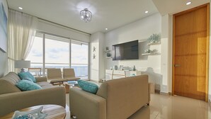 Una sala de estar moderna con un sofá, sillones, una mesa de centro y un televisor montado en la pared.