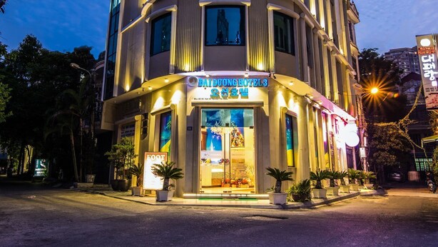 Een meerlaags hotel met verlichte reclameborden, grote ramen en een goed verlichte ingang.