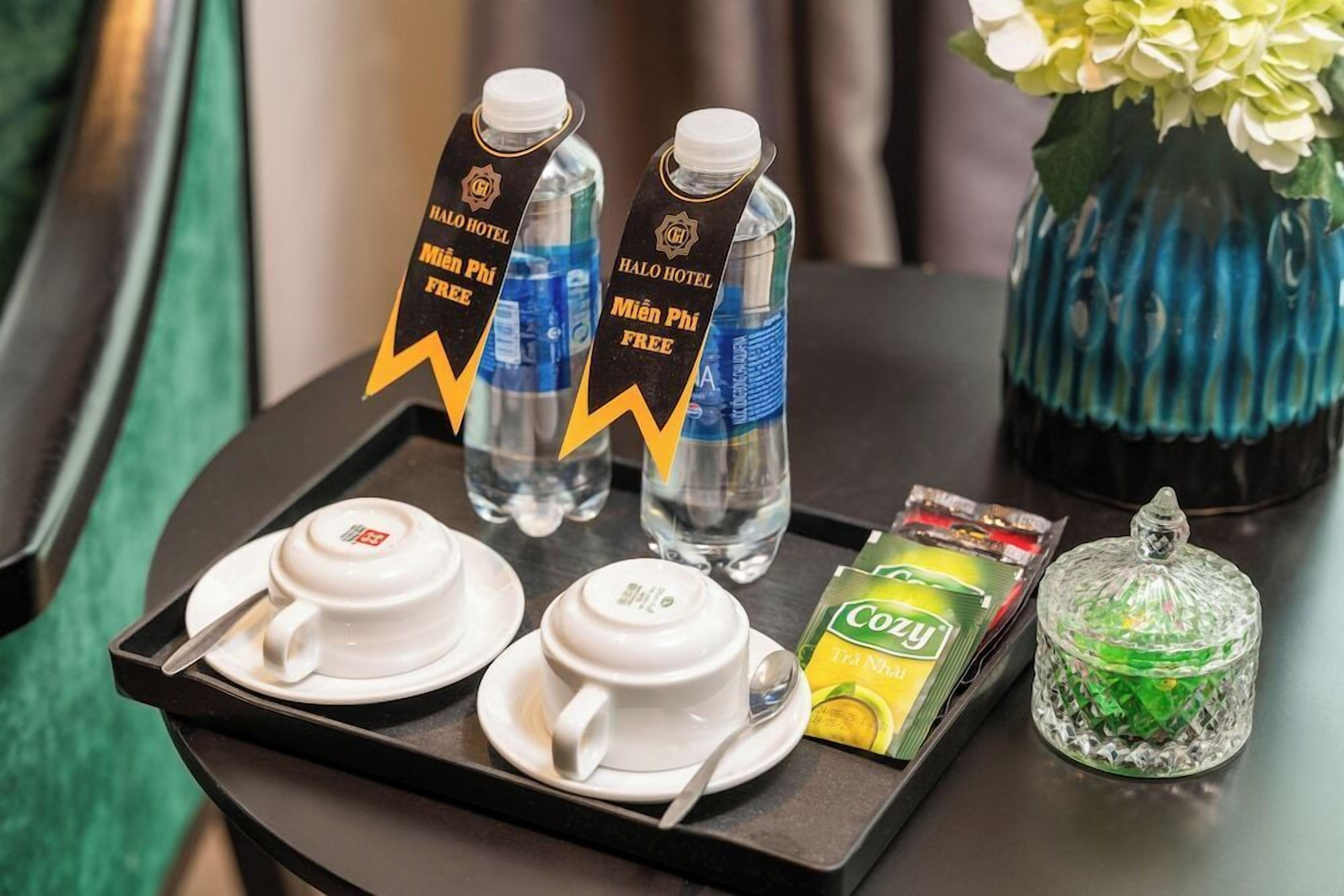 A tray with two teacups, two water bottles, a box of Cozy tea, and a glass jar on a table.