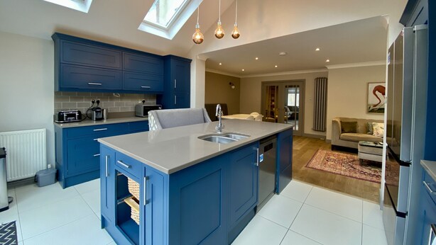 A modern kitchen with blue cabinets, a central island, and skylights.