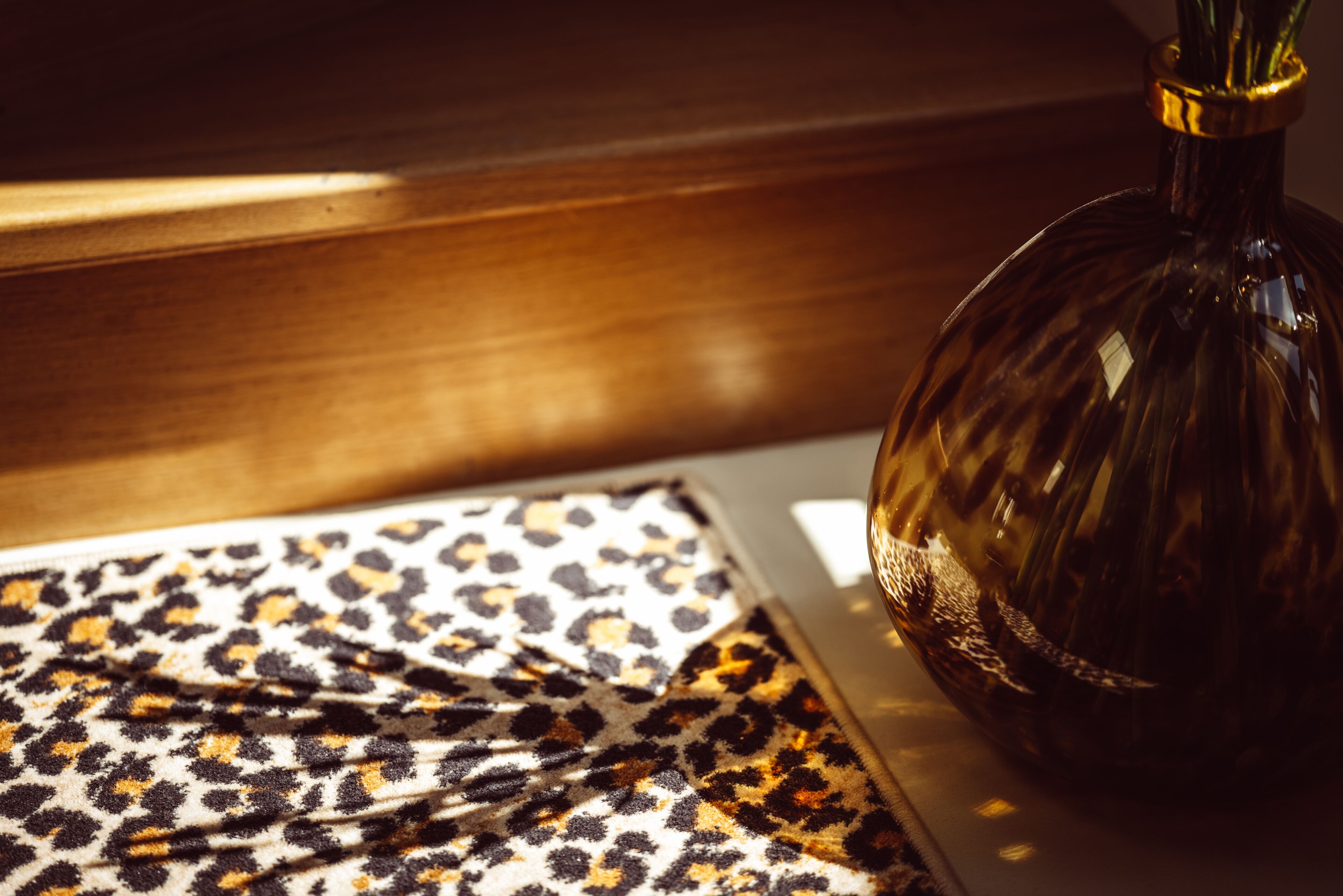 A wooden surface with a patterned fabric and a glass vase.