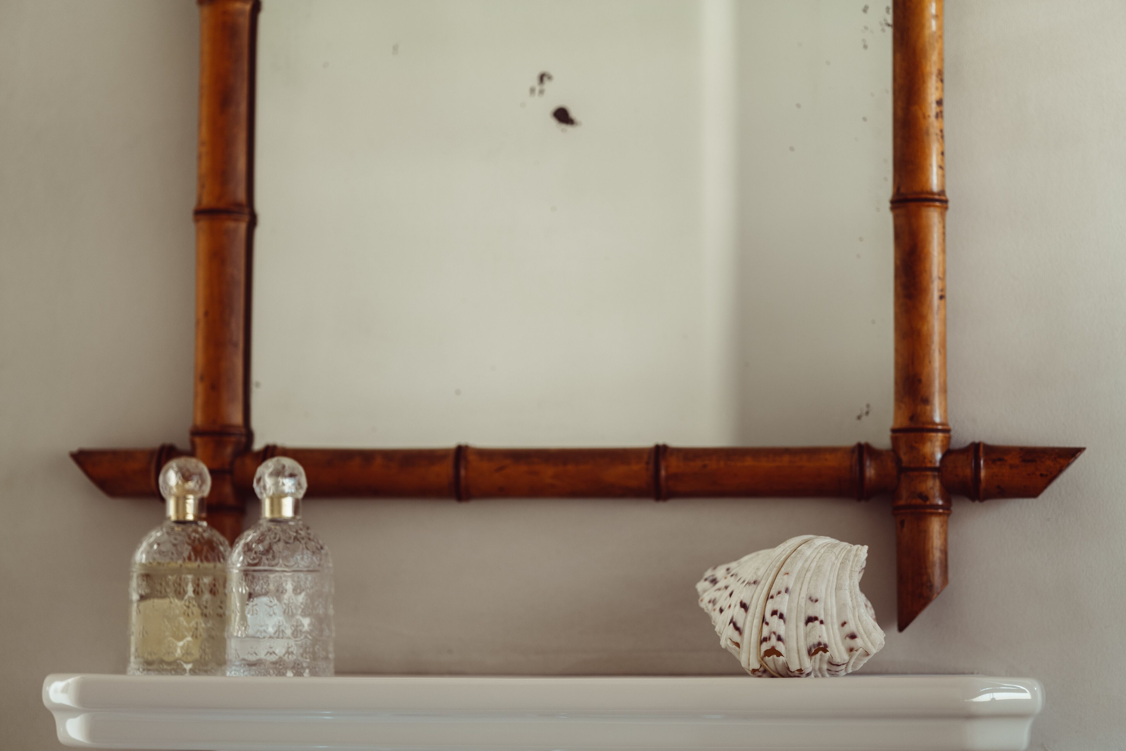 A bathroom with a white sink, two glass bottles, and a decorative shell.