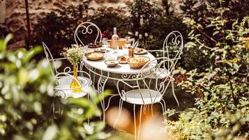 Une table ronde en métal, entourée de chaises et de verdure, dans un cadre extérieur.