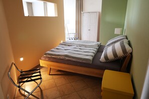 A bedroom with a bed, a chair, a wardrobe, and a bedside table.