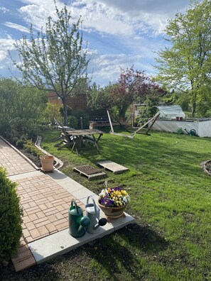 A well-maintained backyard with a lawn, a wooden deck, and a flower pot.