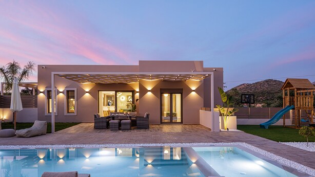A modern outdoor pool area with a patio, seating, and a slide.