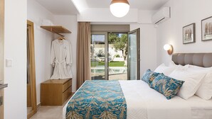 A bedroom with a bed, a robe hanging on a rack, a bedside table, and a view of the outdoors through a glass door.