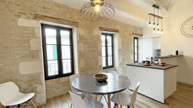 Una cucina moderna con isola centrale, sedie bianche e tavolo da pranzo.