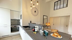 Una cucina moderna con un'isola grande, forno integrato e una lampada a sospensione.